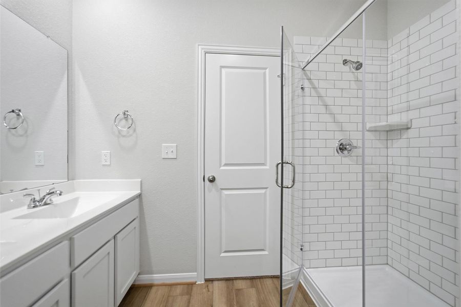 Bathroom featuring vanity, a stall shower, and light wood-type flooring