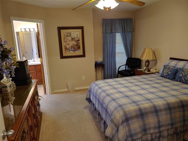 Carpeted room with a ceiling fan light fixture and a window with blinds