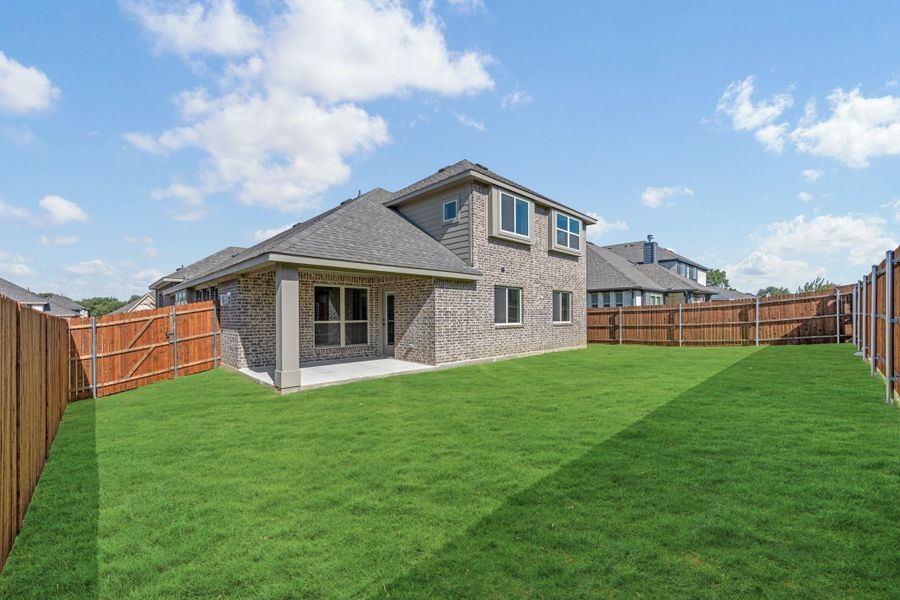 Two-story brick home with covered patio, large grassy backyard, and wood privacy fence Two-story brick home with covered patio, large grassy backyard, and wood privacy fence