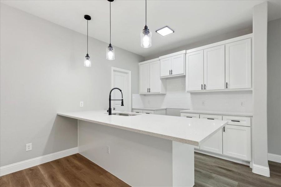 Kitchen featuring decorative light fixtures, white cabinetry, sink, kitchen peninsula, and dark wood-type flooring