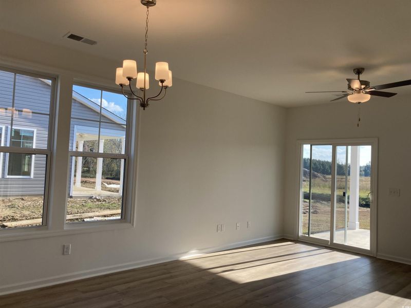 Unfurnished dining area featuring a chandelier, dark wood finished floors, and ceiling fan