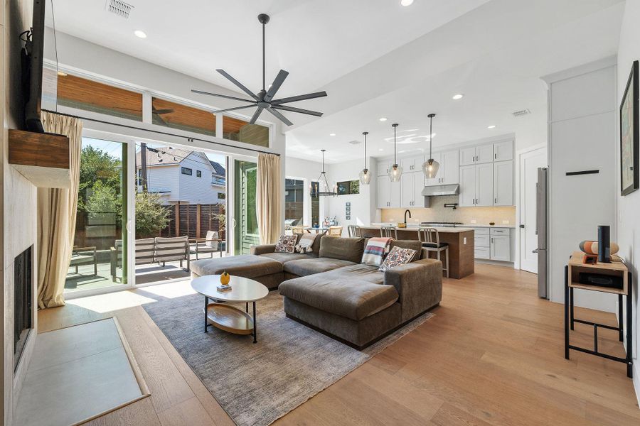 Living room with recessed lighting, light wood finished floors, a chandelier, a ceiling fan, and a fireplace