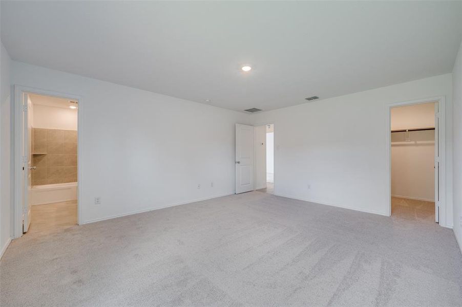 Unfurnished bedroom with a closet, carpet floors, connected bathroom, and a walk in closet Unfurnished bedroom with a closet, carpet floors, connected bathroom, and a walk in closet