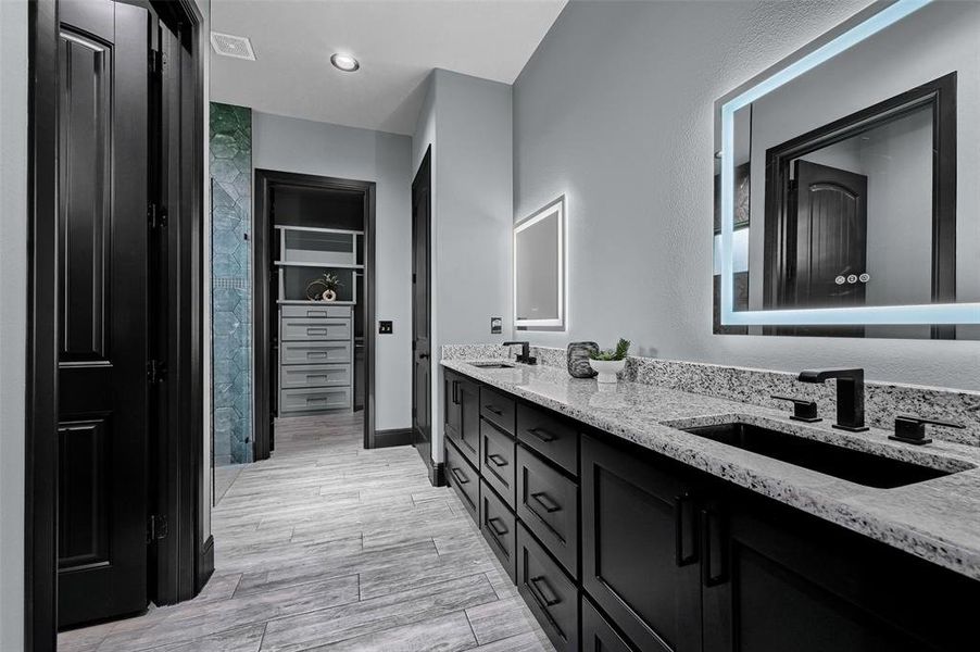 Bathroom featuring double vanity, wood finished floors, and a walk in closet Bathroom featuring double vanity, wood finished floors, and a walk in closet