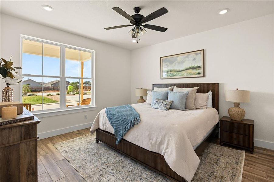 Bright room featuring a large window, a ceiling fan with integrated lighting, recessed ceiling lights, wood-finish flooring, and white baseboards