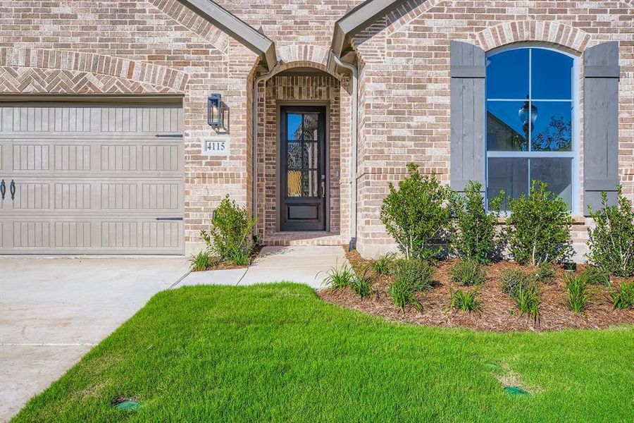 Property entrance with brick siding, driveway, and an attached garage