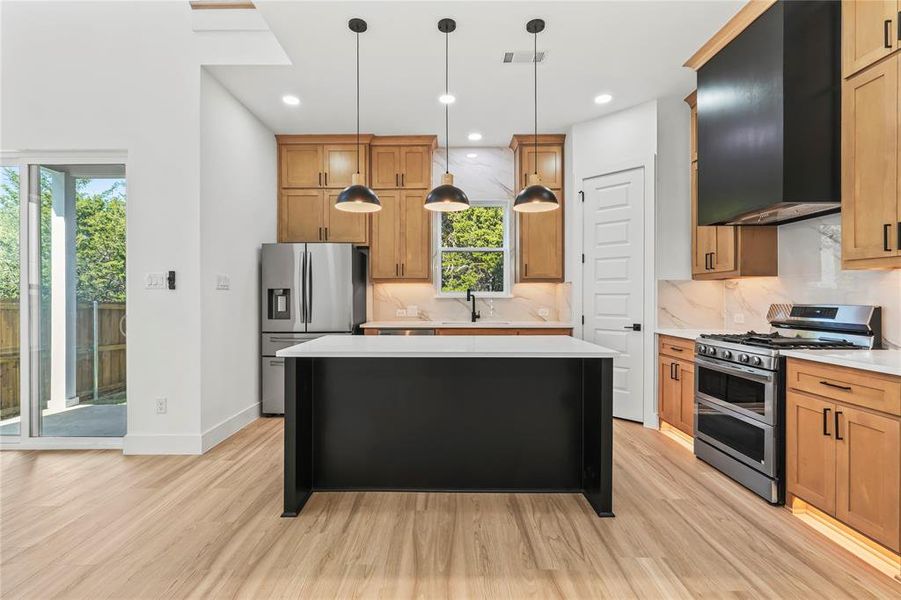 Kitchen featuring a center island, hanging light fixtures, stainless steel appliances, recessed lighting, and light wood-style floors