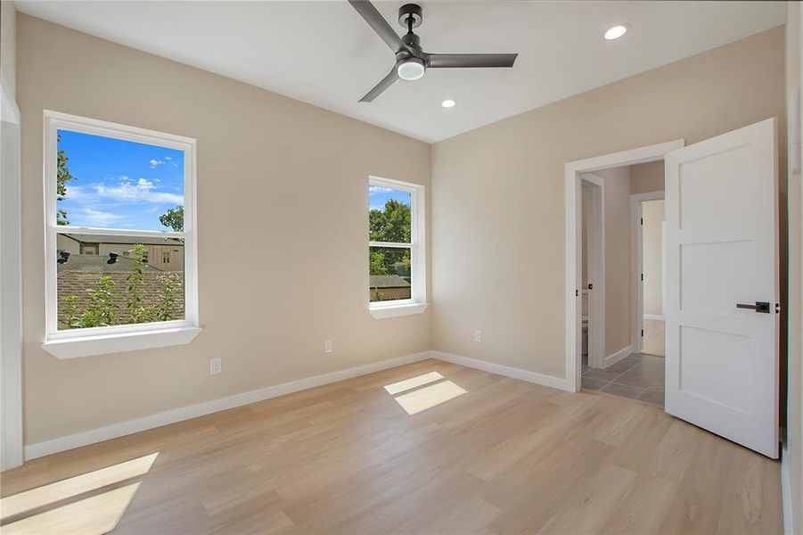 Unfurnished bedroom with light wood-type flooring, multiple windows, and ceiling fan