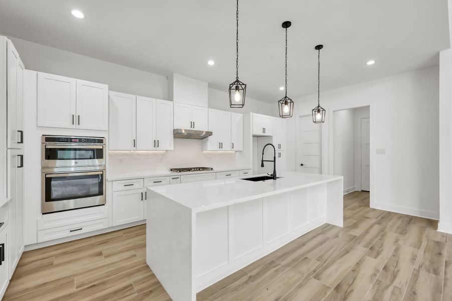 Well-designed kitchen layout offering abundant storage, designer lighting, and a large island overlooking the main living area.