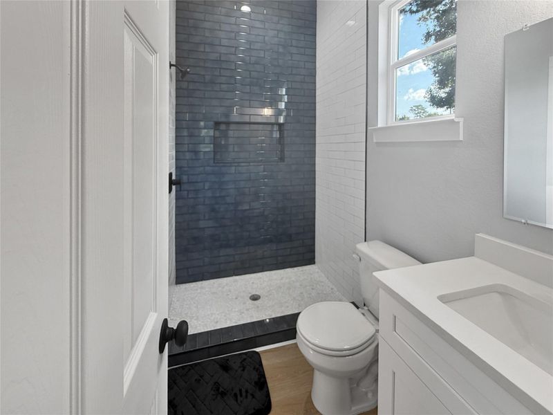 A beautifully upscale bathroom featuring a modern subway tile shower with black fixtures, and bright natural light streaming through the window for a fresh and inviting ambiance.