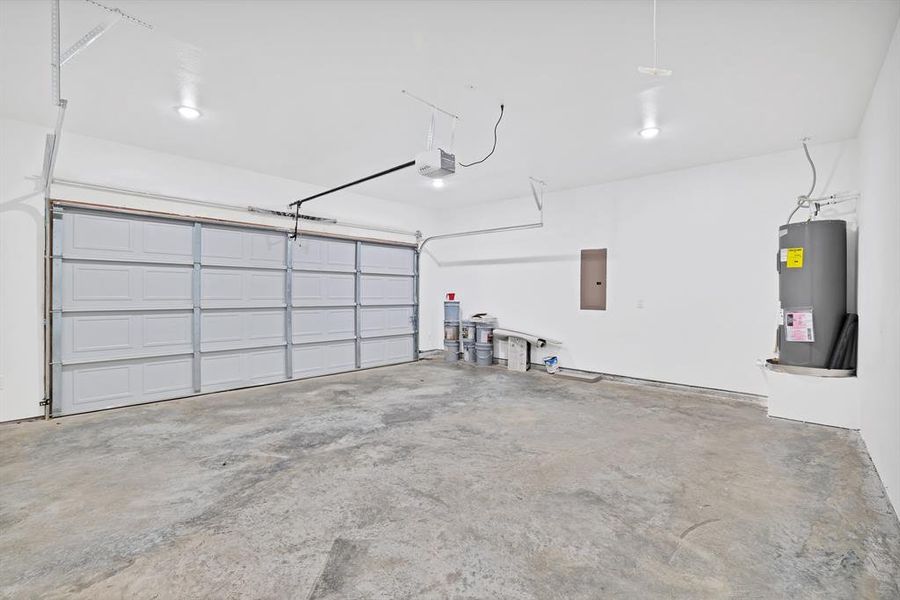 Garage featuring electric panel, electric water heater, and a garage door opener