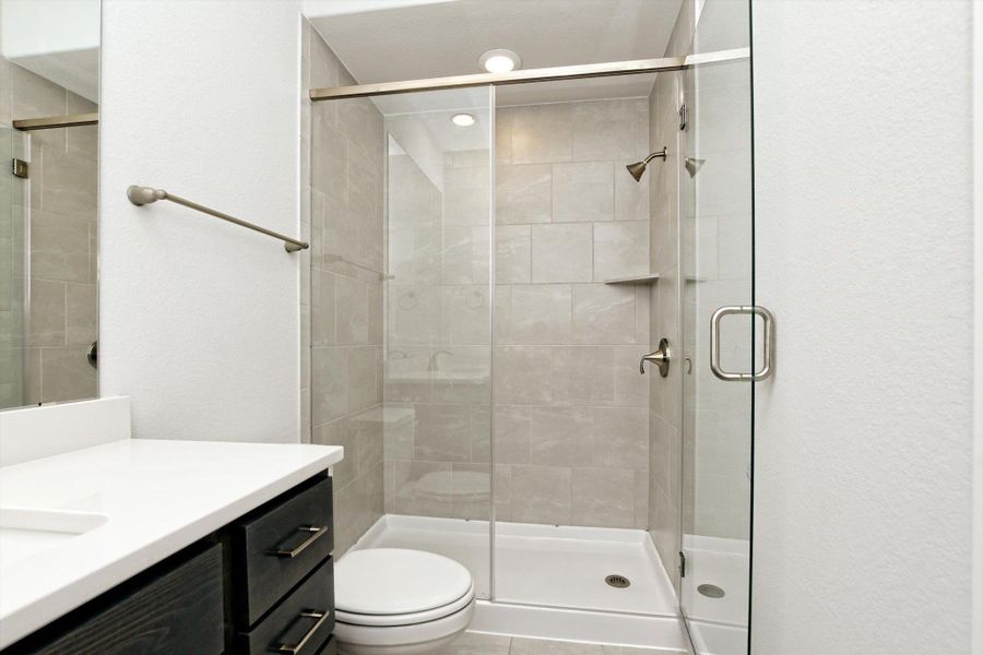 Full bath with a stall shower, toilet, and vanity