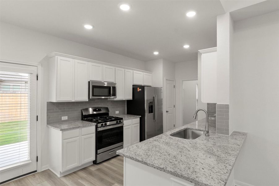 Kitchen with stainless steel appliances, decorative backsplash, a peninsula, white cabinetry, and recessed lighting Kitchen with stainless steel appliances, decorative backsplash, a peninsula, white cabinetry, and recessed lighting
