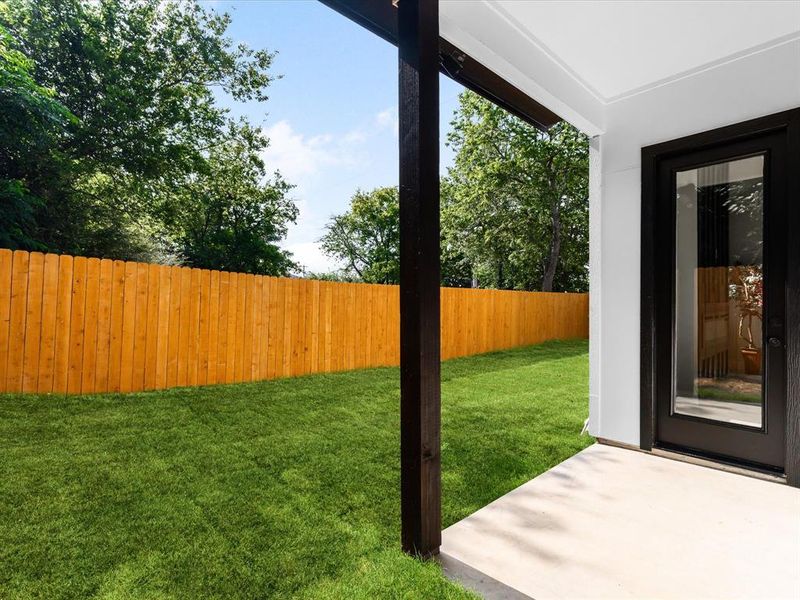 Private backyard featuring a new wood fence, lush green lawn, and mature trees