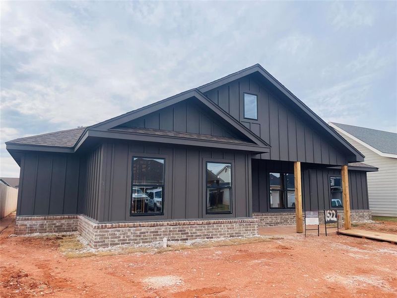 View of property exterior with board and batten siding, a porch, brick siding, and roof with shingles View of property exterior with board and batten siding, a porch, brick siding, and roof with shingles