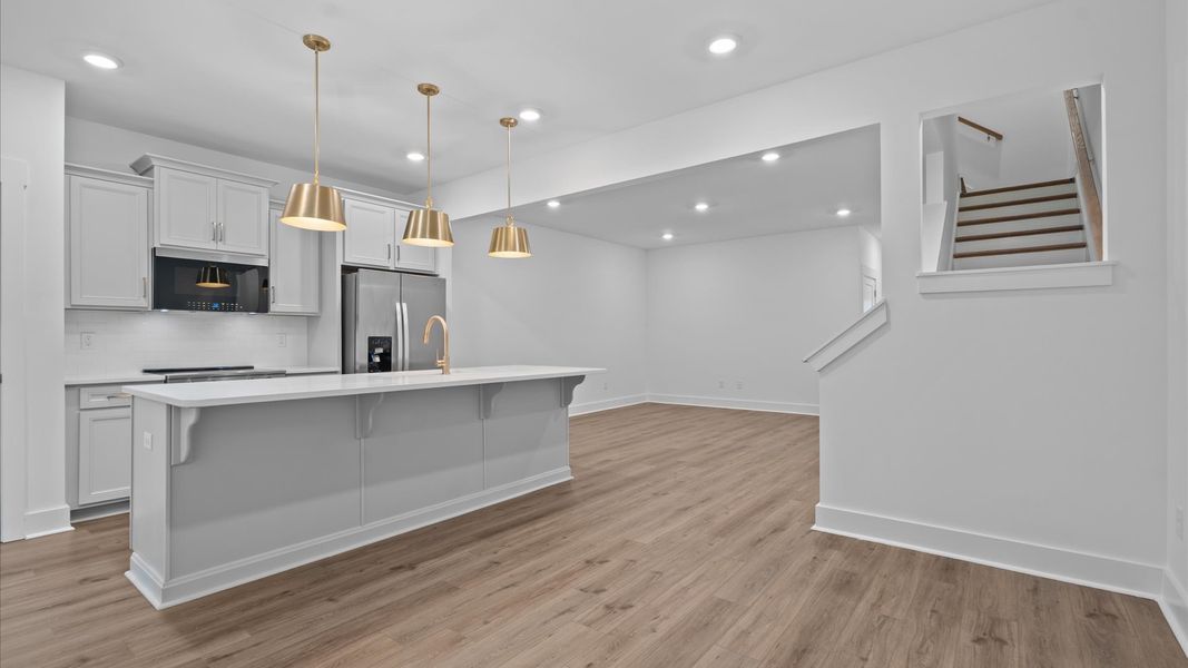 Tasteful design meets functional luxury in this kitchen with a 9-foot island and modern pendant lighting Tasteful design meets functional luxury in this kitchen with a 9-foot island and modern pendant lighting