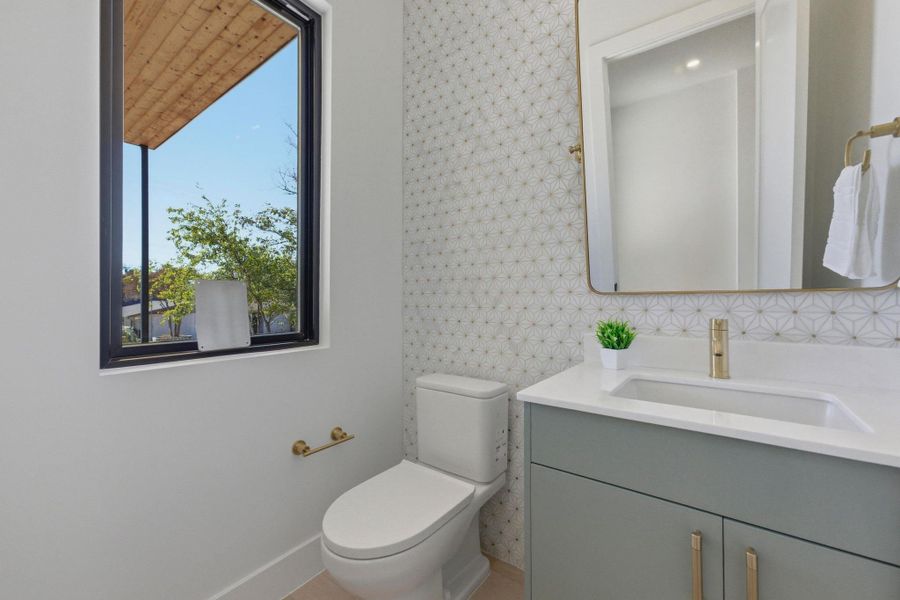 Half bathroom featuring vanity and wallpapered walls