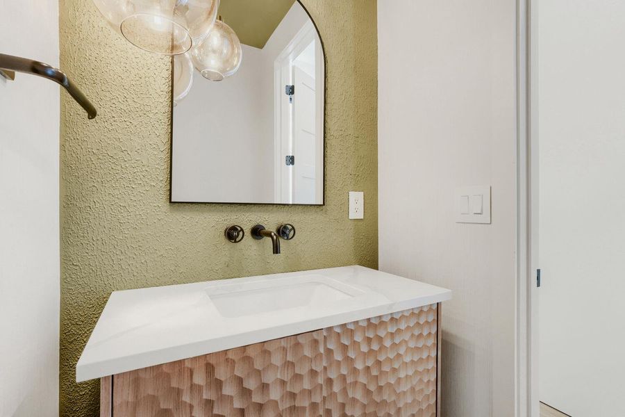 Bathroom off kitchen featuring vanity and a textured wall Bathroom off kitchen featuring vanity and a textured wall