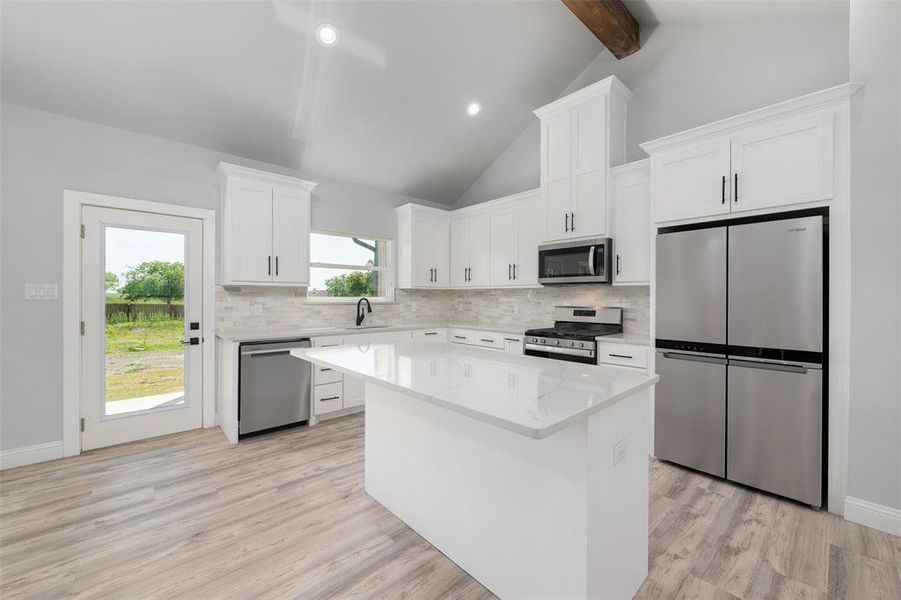 Kitchen with decorative backsplash, stainless steel appliances, a sink, and a kitchen island