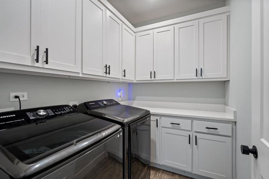 Laundry room with separate washer and dryer, cabinets, and hardwood / wood-style floors