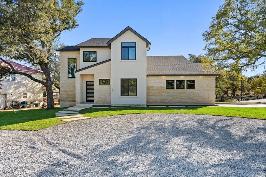 View of front facade with stone siding, a shingled roof, a front lawn, and stucco siding View of front facade with stone siding, a shingled roof, a front lawn, and stucco siding