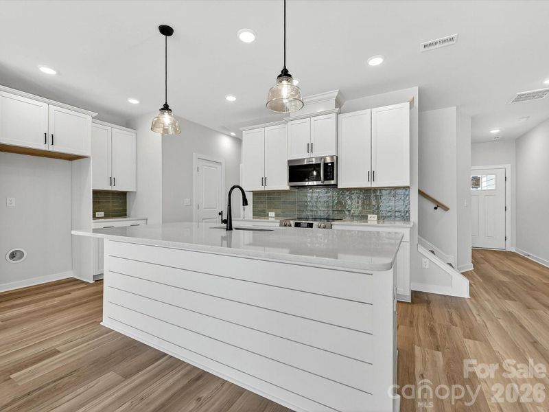 42" White cabinets, Quartz countertops, tiled backsplash. Large kitchen island with shiplap accent, Frigidaire Appliances. Cooking is exhaust vented to the outside