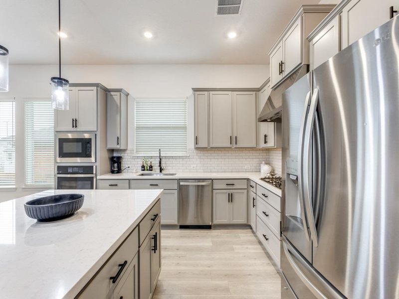 The kitchen features quartz counters, classic white subway tile, a center island, walk-in pantry and SS appliances.