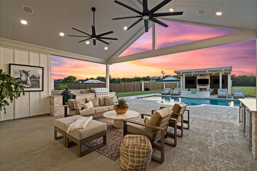 An inviting outdoor living space with a covered patio, a well-appointed outdoor kitchen, and a sparkling pool, all set against a vibrant sunset. An inviting outdoor living space with a covered patio, a well-appointed outdoor kitchen, and a sparkling pool, all set against a vibrant sunset.