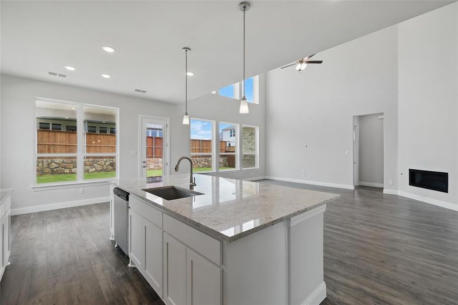 Kitchen with a sink, healthy amount of natural light, baseboards, ceiling fan, and a towering ceiling Kitchen with a sink, healthy amount of natural light, baseboards, ceiling fan, and a towering ceiling