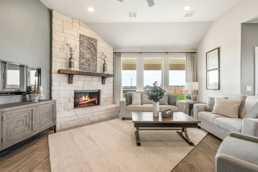 Living room with floor-to-ceiling stone fireplace, gray sofas, wood coffee table, and large windows with natural light