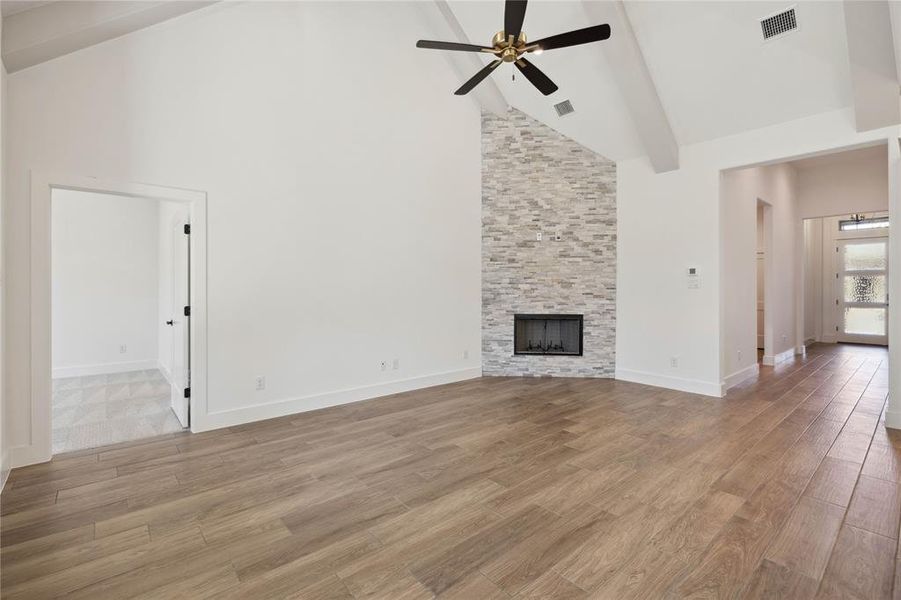 Unfurnished living room featuring ceiling fan, a fireplace, high vaulted ceiling, and light hardwood / wood-style floors