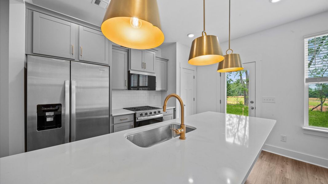 Gold accented kitchen with 9 foot island in two story townhome at Ransdell Pointe by DRB Homes in Spartanburg, SC