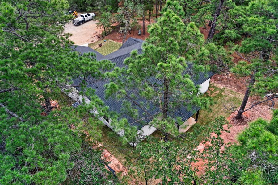 Contemporary residence featuring a dark shingle roof, white exterior siding, and a covered porch Contemporary residence featuring a dark shingle roof, white exterior siding, and a covered porch