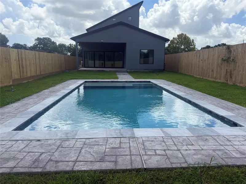 Enjoy a refreshing retreat in this backyard oasis featuring a sleek, modern pool with stylish decking, perfectly complementing the contemporary home and private fenced yard.
