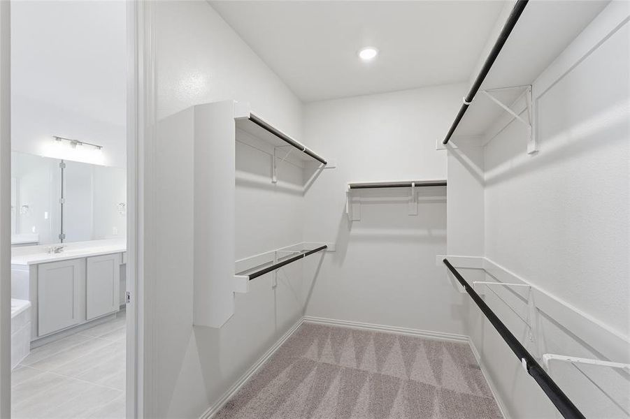 Walk-in closet featuring extensive shelving, multiple hanging rods, recessed lighting, and patterned carpeting