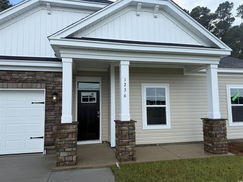 Doorway to property with a porch, an attached garage, and stone siding Doorway to property with a porch, an attached garage, and stone siding