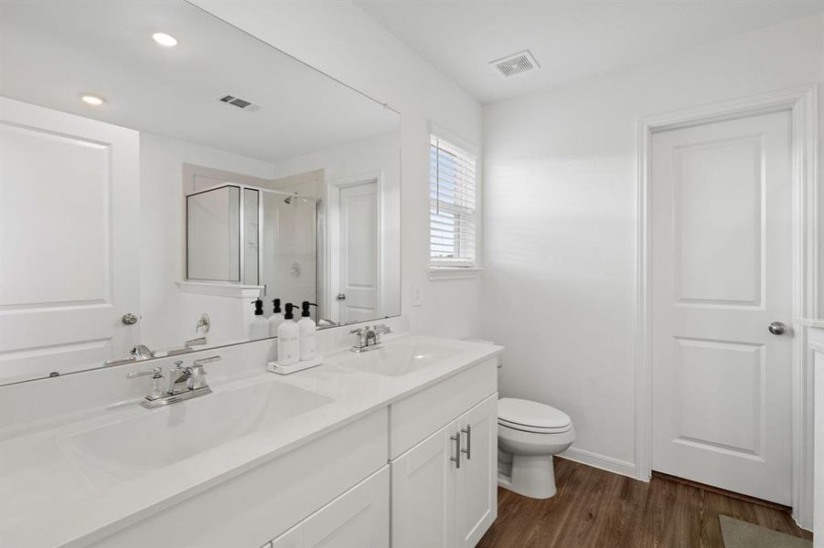 The Primary Bath Oasis features dual vanities with extended countertops, glass encased walk-in shower with tile surround, separate soaking tub and modern finishes throughout.