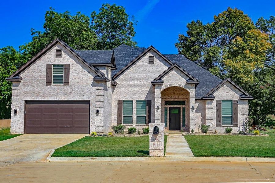 French country style house with brick siding, a front yard, driveway, and a garage French country style house with brick siding, a front yard, driveway, and a garage