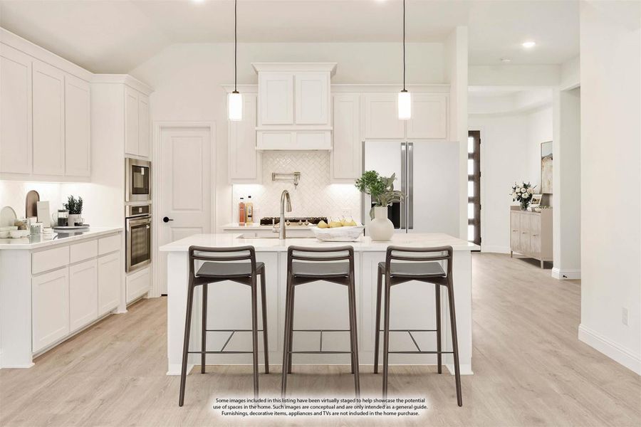White kitchen with center island, three bar stools, pendant lights, and stainless steel appliances on light wood floors