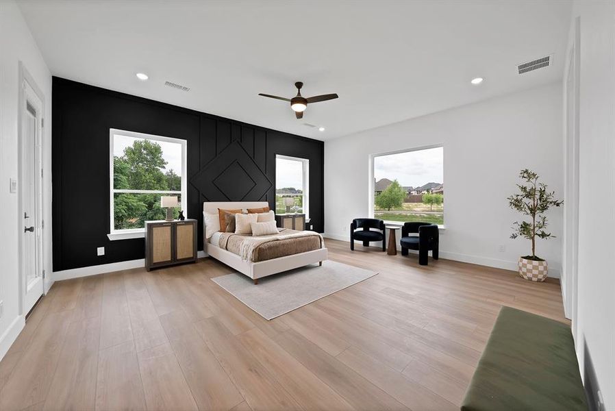 Spacious room featuring wood-finish flooring, a decorative accent wall, ample natural light from multiple windows, recessed lighting, and a ceiling fan