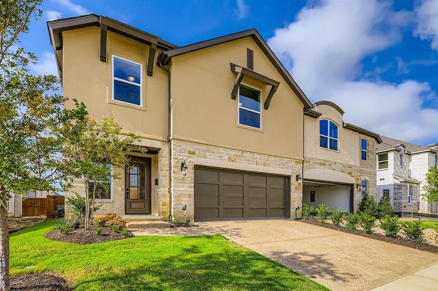 View of front of property with a garage, stone siding, stucco siding, and concrete driveway