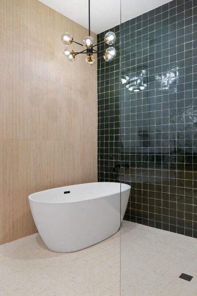 Bathroom featuring tiled shower, a soaking tub, and tile walls
