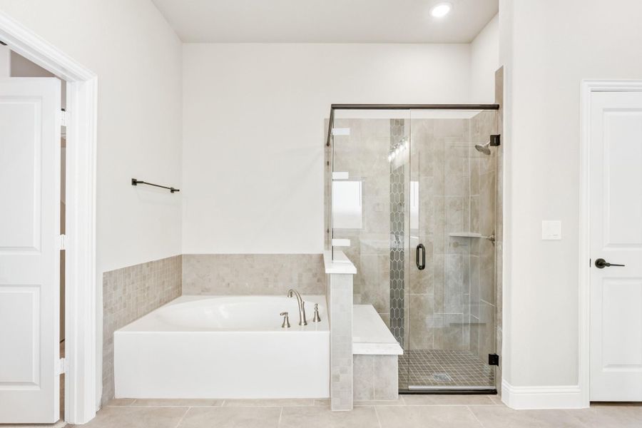 Master bathroom with soaking tub, glass-enclosed tile shower, and white walls