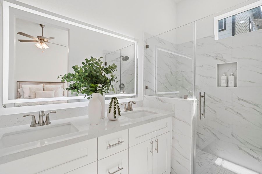 Primary bathroom is an oasis with dual vanities and frameless, walk-in shower