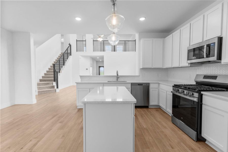Stunning gourmet kitchen featuring tall white shaker cabinets, gorgeous granite countertops, island, stainless steel appliances, and subway glass tile backsplash — perfect for creating culinary delights. **Image Representative of Plan Only and May Vary as Built**.
