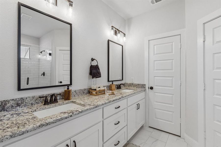 Bathroom featuring a shower, double vanity, and tile patterned floors