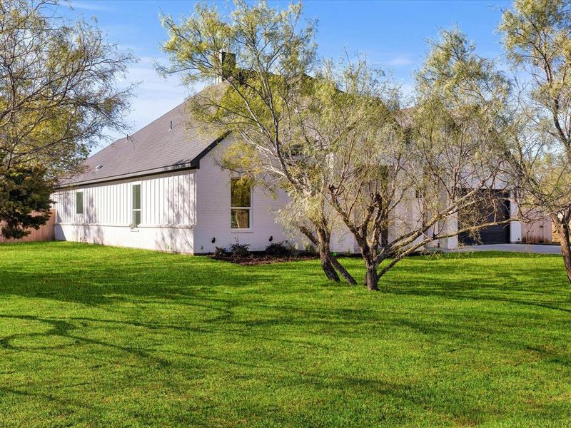 View of property exterior featuring a yard, a chimney, and a garage