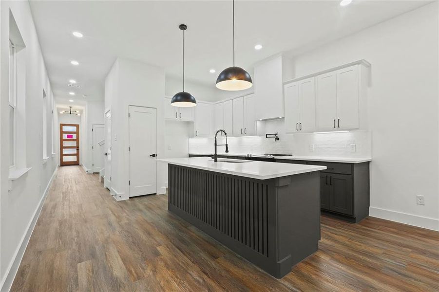 Kitchen with white cabinets, decorative light fixtures, gray cabinetry, backsplash, and a kitchen island with sink