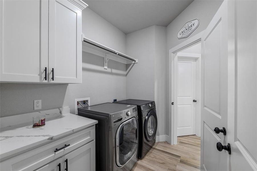 Laundry area with cabinets, separate washer and dryer, and light hardwood / wood-style flooring