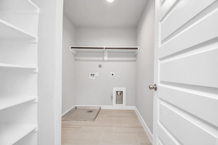 A perfect blend of functionality and comfort. Laundry room, thoughtfully equipped with shelving for effortless organization. Both gas and electric connections available. Sample photo of completed home with similar floor plan. Actual colors and selections may vary.